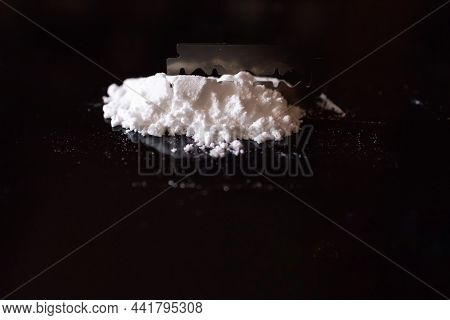 Razor Blade On Drug Powder On Reflection Black Background.copy Space.
