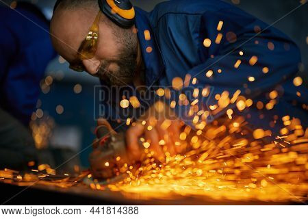 Close Up Of Worker With Headphone In Dark Blue Uniform Doing Gate By Electric Steel Cutter Machine F