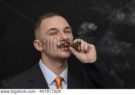 Portrait Of A 30-35-year-old Man Smoking A Thick Cigar With A Curled Mustache On A Black Background,