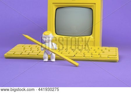 A Baby Figurine With A Pencil On The Background Of A Monitor And A Computer On A Purple Background. 