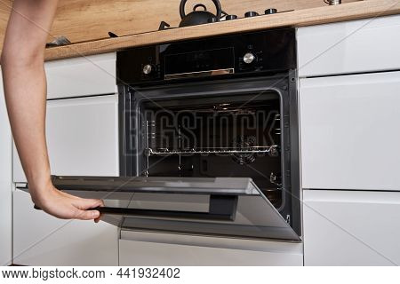 Woman Hand Open Electric Oven Door With Handle. Homemade Cooking. Kitchen Appliance