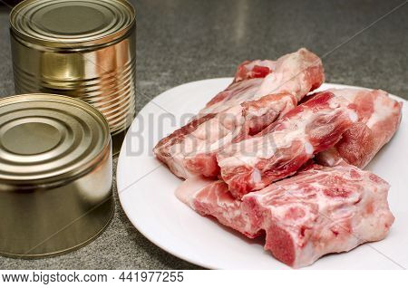 Chunks Of Raw Pork And Cans Of Stews. Preparation Of Food For Long-term Storage.