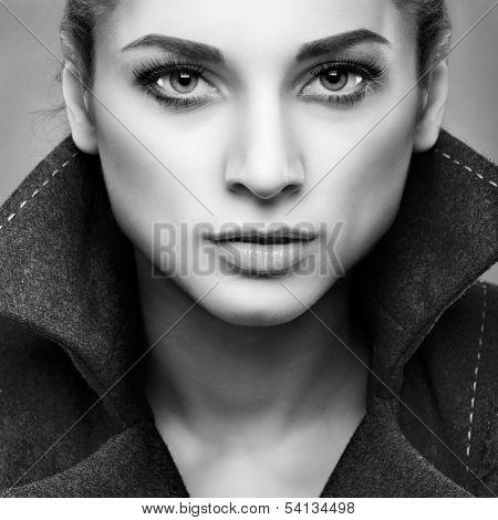 Portrait of elegant young woman in a grey overcoat  on a grey background