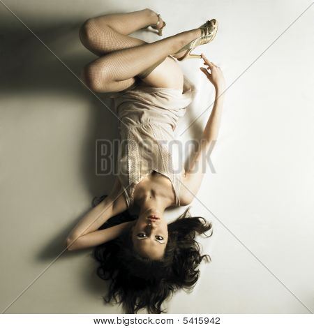 Young Seductive Woman Lays On White Bedsheet