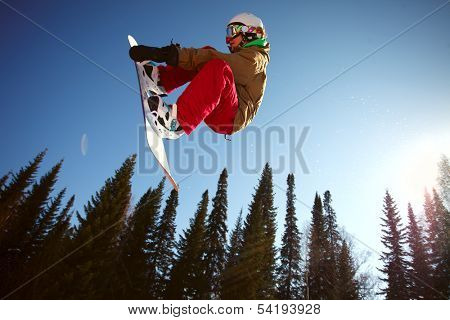 Snowboarder jumping through air with deep blue sky in background