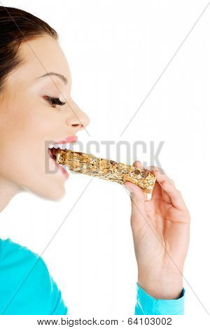 Young woman eating Cereal candy bar, isolated on white 