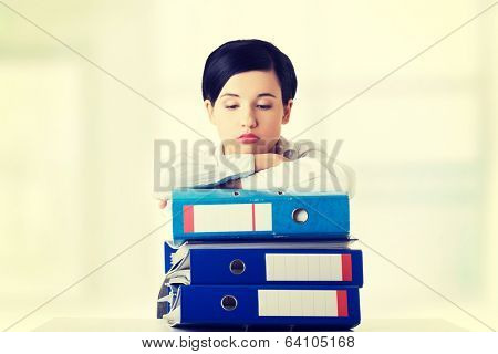 Sad woman with ringbinders sitting at the desk. Tired and exhousted business woman. 