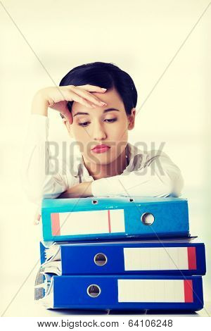 Sad woman with ringbinders sitting at the desk. Tired and exhousted business woman.