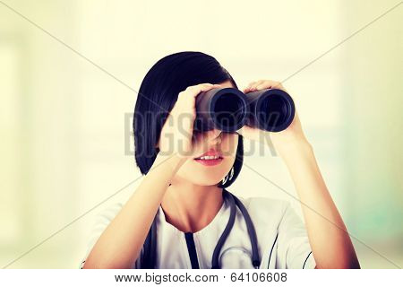 Atractive medical girl looking through binoculars