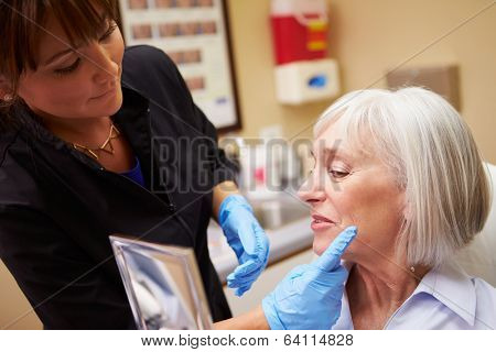 Female Client Looking In Mirror After Botox Treatment