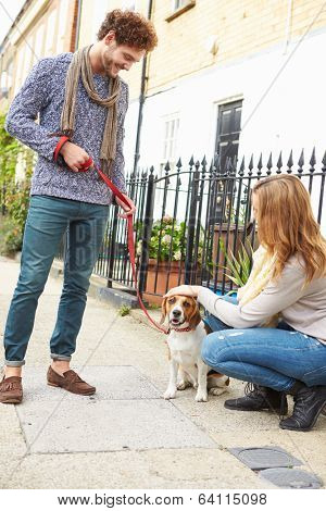 Couple Taking Dog For Walk On City Street