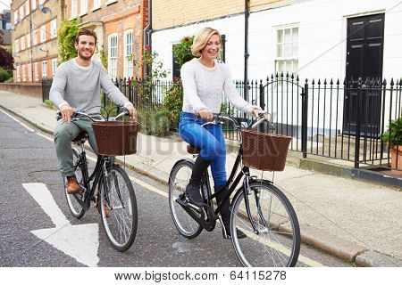 Couple Cycling Along Urban Street Together