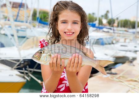 Happy kid fisherwoman with dentex fish catch in Mediterranean marina