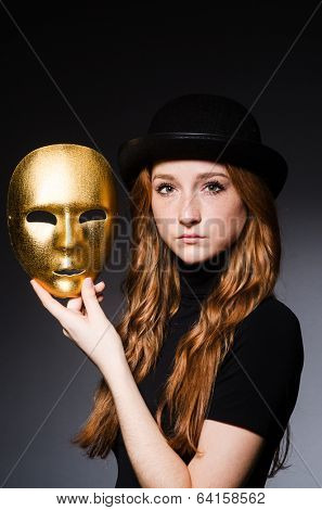 Redhead woman in hat  iwith mask in hypocrisy consept against dark  grey background