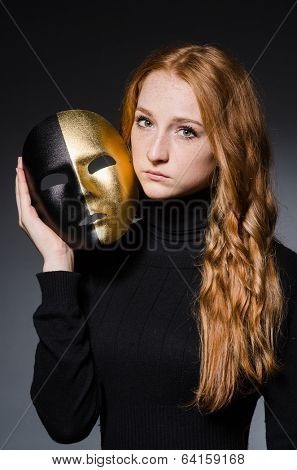 Redhead woman iwith mask in hypocrisy consept against grey background