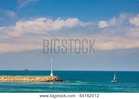 Beacon on breakwater and small yacht on Mediterranean sea along coast of Ashkelon, Israel.