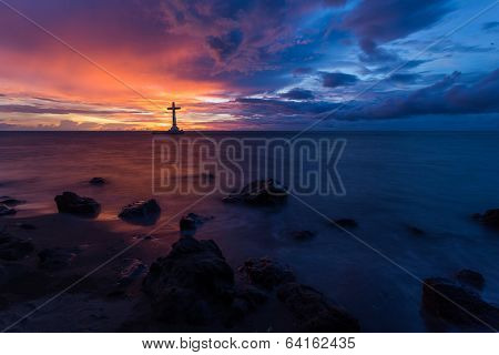 Catholic cross silhouette in a sunken cemetery at dusk, Camiguin island, Philippines