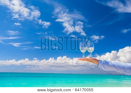 Two glasses on hand on blue sky background