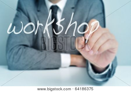 man wearing sitting in a desk writing the word workshop in the foreground
