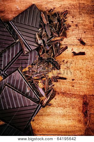 Chopped Chocolate Bar On Wooden Background Closeup. Broken Dark Chocolate Bar On Wood Table Macro.