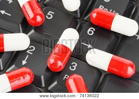 Pills on computer keyboard - concept technology background