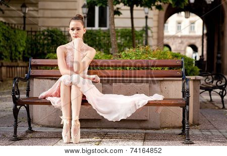 Young beautiful ballerina relaxing on bench