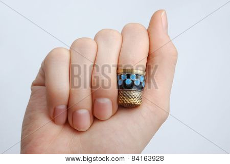 hand, a thimble on her finger