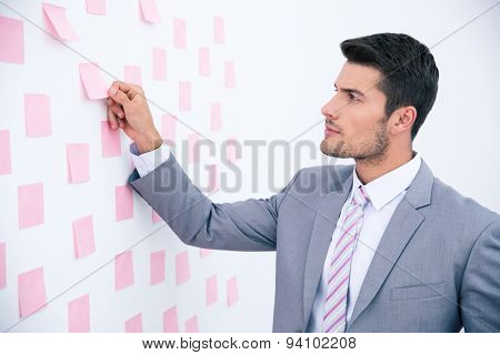 Handsome businessman looking on sticker at wall in office