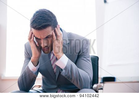 Pensive businessman sitting on office chair in office