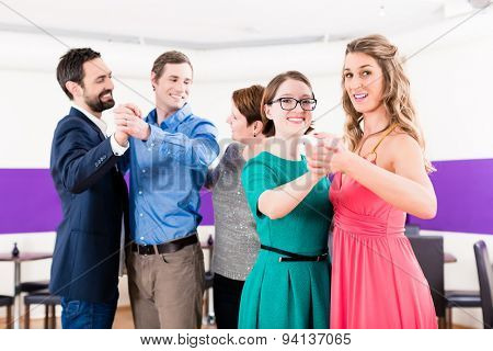 Dance instructor with gay couples in dancing class
