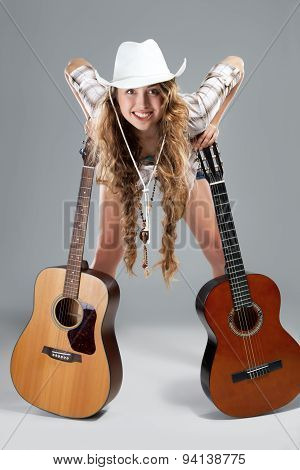 Sesy cowgirl in cowboy hat with acoustic guitar