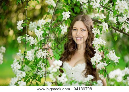 Young spring fashion woman in spring garden Springtime Summertime Trendy girl in the flowering trees in then at sunset in spring summer landscape background Allergic to pollen of flowers Allergy 