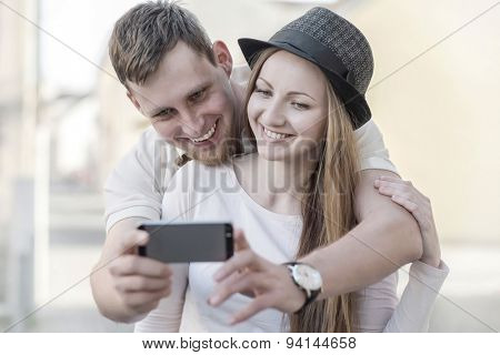 Touristic couple shooting on the modile phone at the city streets under sunlight.