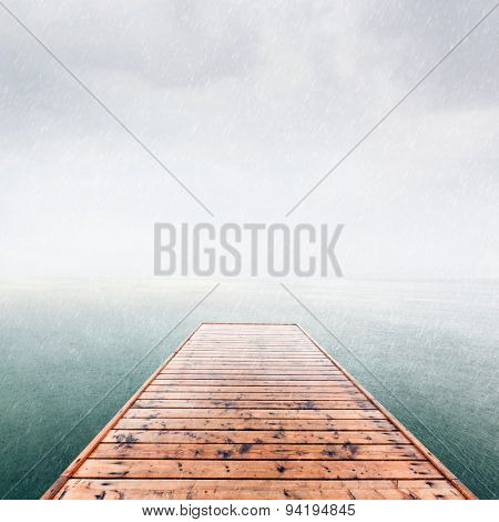 Wooden jetty, pier on deep cold sea, ocean. Raining sky, scandinavian mood, copy-space.