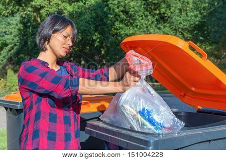 European woman throwing plastic garbage in container