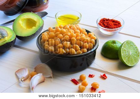 Ingredients for cooking delicious Avocado hummus. Chickpeas olive oil lemon juice garlic and spices on wooden background. Healthy eating.