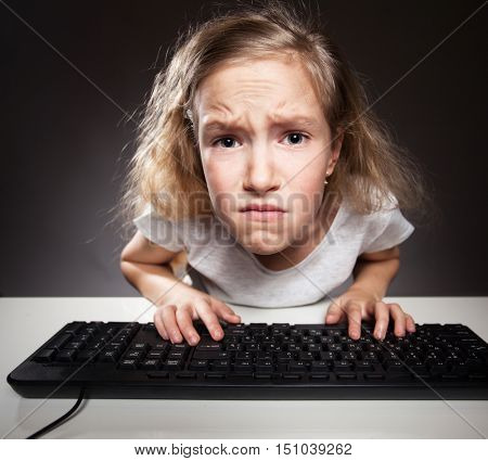 Child with discontent looks at the computer. Computer addiction