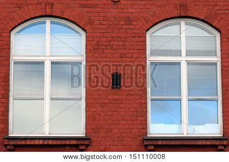 Two old windows in a brick walled building.