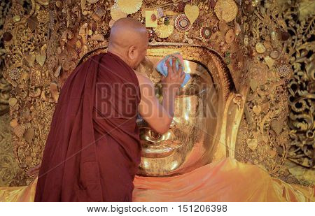 MANDALAY, MYANMAR - DECEMBER 2015: Mahamuni Buddha image is being worshiped by the head monk; part of a daily washing ritual in Mahamuni temple, Mandalay, Myanmar.