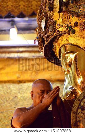 MANDALAY, MYANMAR - DECEMBER 2015: Mahamuni Buddha image is being worshiped by the head monk; part of a daily washing ritual in Mahamuni temple, Mandalay, Myanmar.