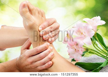Macro close up of therapist doing healing foot massage against green background.
