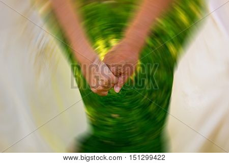 Concept shoot of friendship and love of old man and woman: two hands over green grass. Image blurred in postproduction
