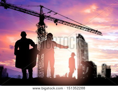Silhouette engineer looking construction worker under tower cran in a building site over Blurred construction worker on construction site