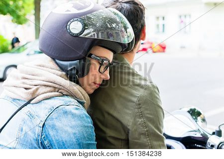 Young woman with helmet sitting on pillion seat of Vespa in streets of Berlin