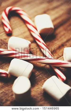 Candy cane with white marshmallows and christmas decoration winter holidays symbol on wooden vintage background with copy space and snow.