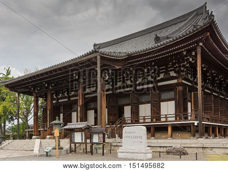 Kyoto Japan - September 15 2016: The main hall of the Kurodani Buddhist Temple offers dark brown wooden structure with white walls. Stairs stelle lantern and signs in front.
