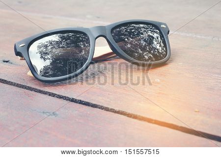 Sunglass On Wood Background. Reflection Shadow Tree In Lens.