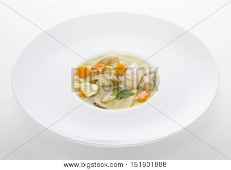 White plate with chicken soup and spoon
