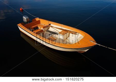 A small open moored motorboat with oars.