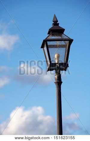 One electric retro lamp post against blue sky.